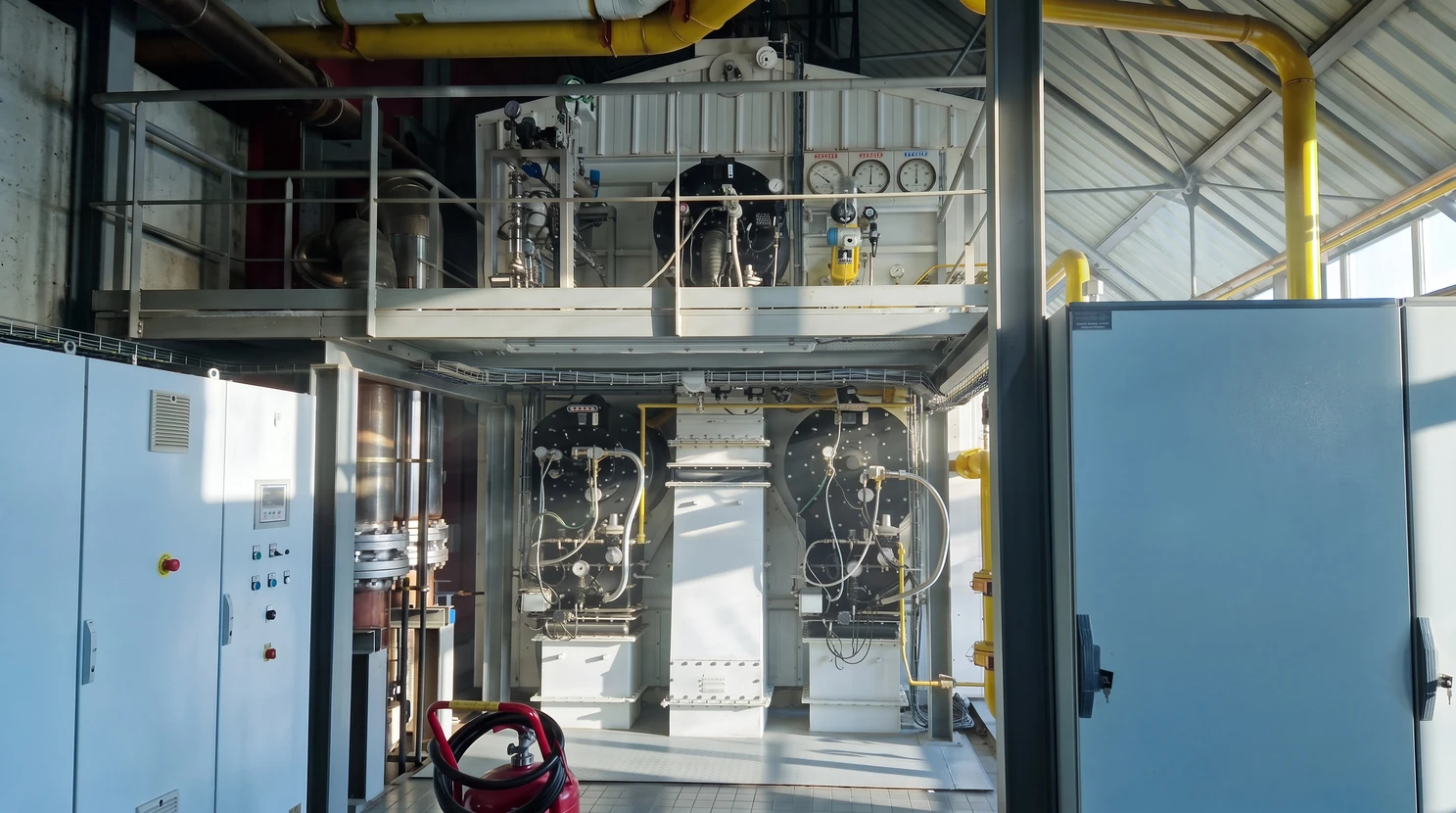 Installation industrielle avec réseau complexe de tuyauteries métalliques isolées thermiquement, vannes de régulation à volant manuel rouge et noir, raccords coudés, système de chauffage ou refroidissement